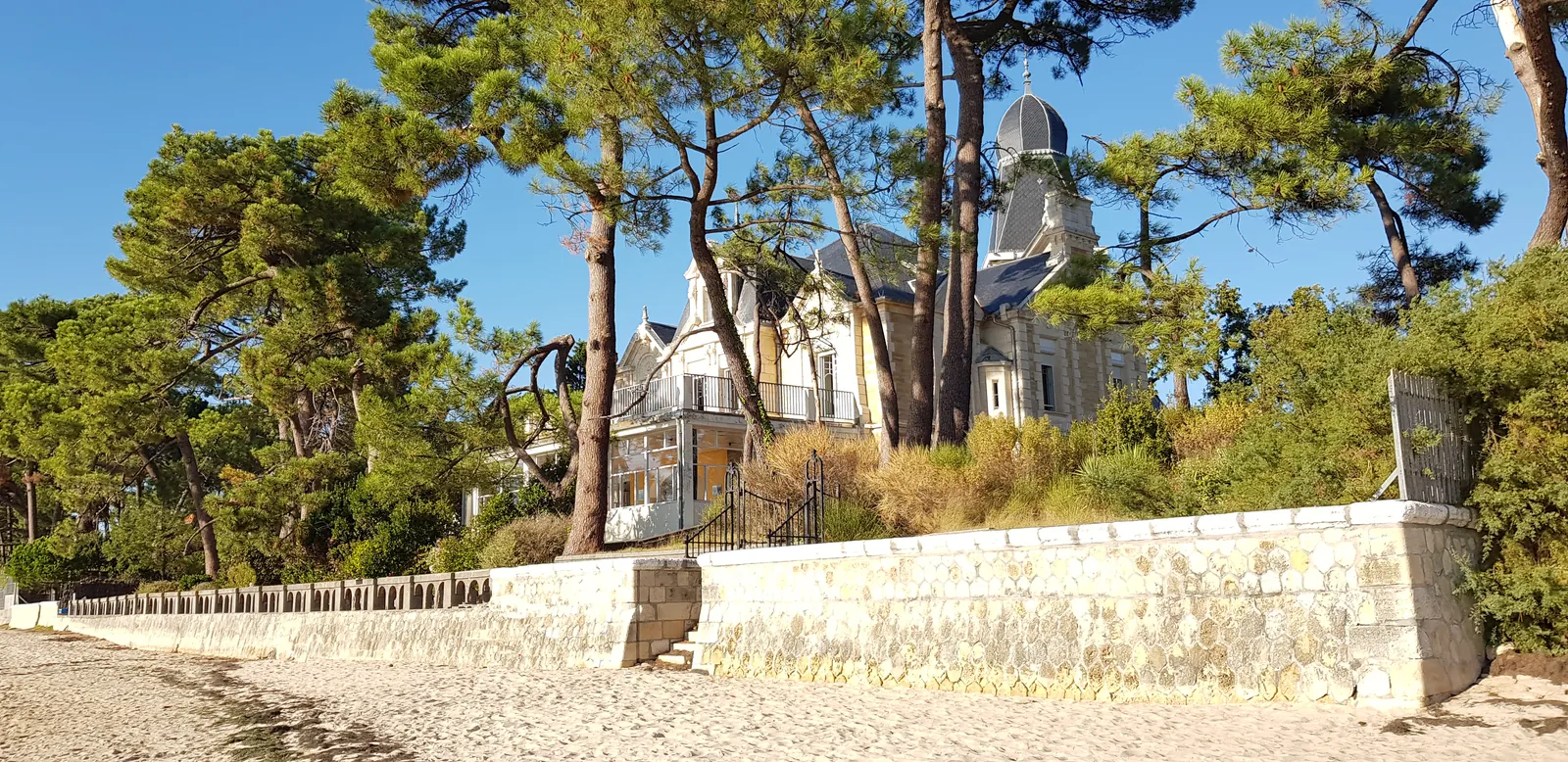 Une villa Belle Époque et sa tour, derrière les pins, au bord de la plage de Taussat